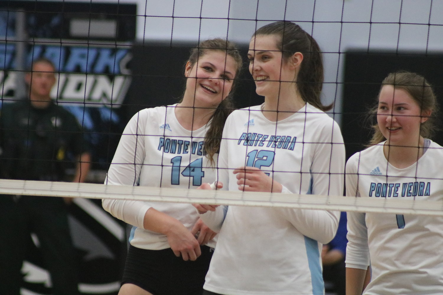 Rachel Johnson (No. 14) shares a laugh with Chelsea Sutton (No. 12) and Ava Grall (No. 1) at the net.